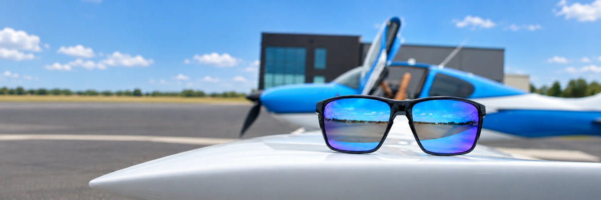 Blue mirrored Torque Fulcrum sunglasses on a white aircraft wing on a sunny day.