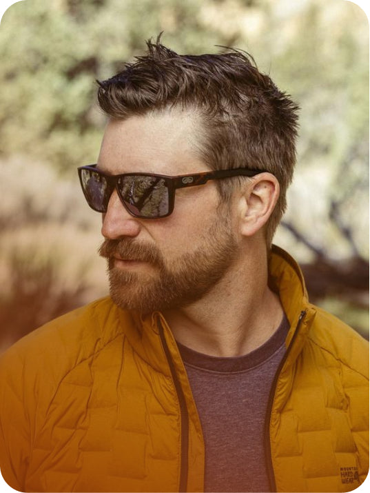 Man wearing tortoise Torque sunglasses and a mustard jacket outdoors