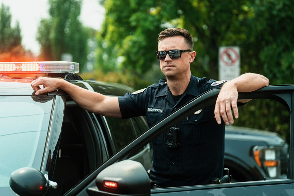Police officer wearing Fulcrum sunglasses standing in an open patrol car door