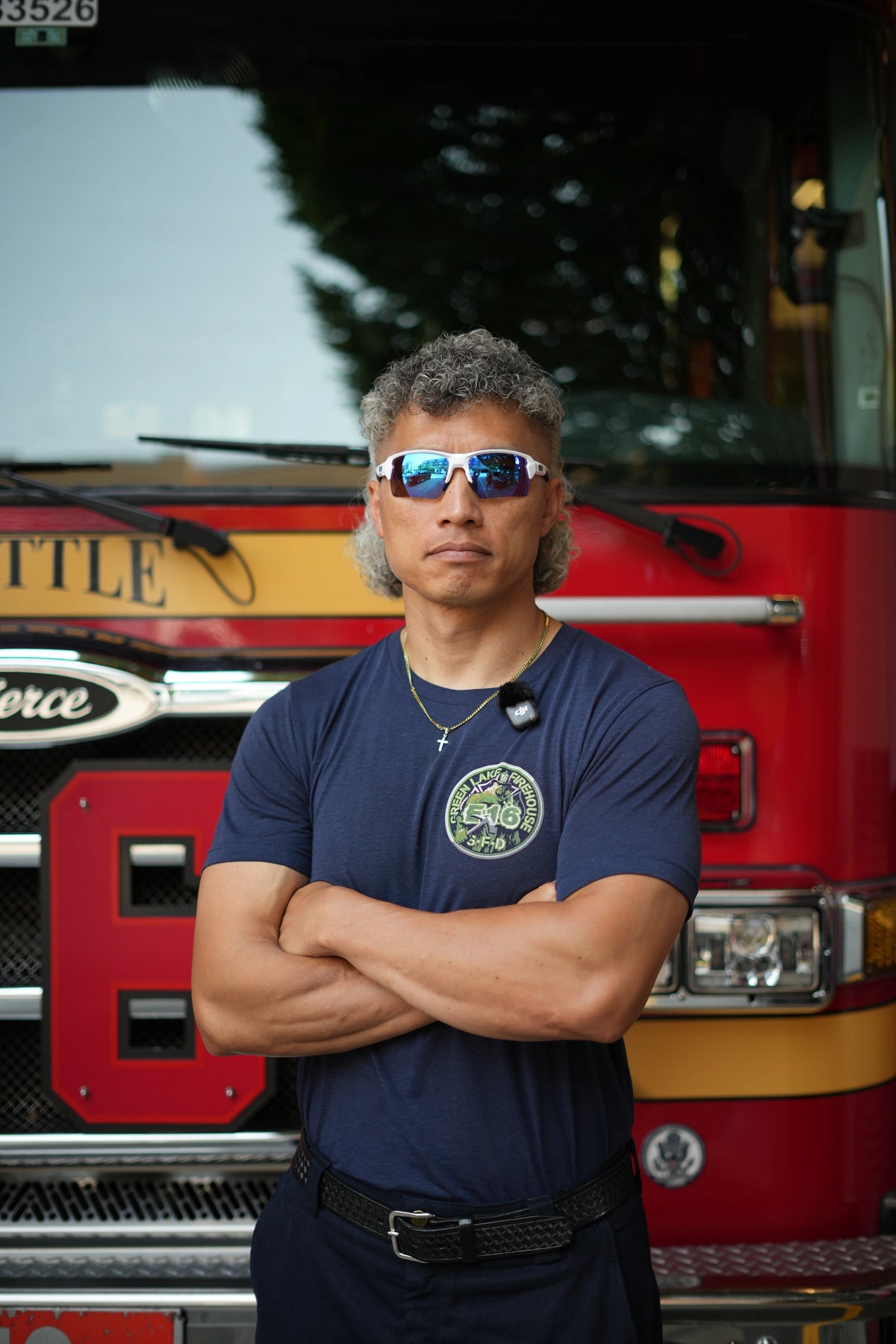 Firefighter wearing white Camber sunglasses with blue mirrored lenses beside a fire engine