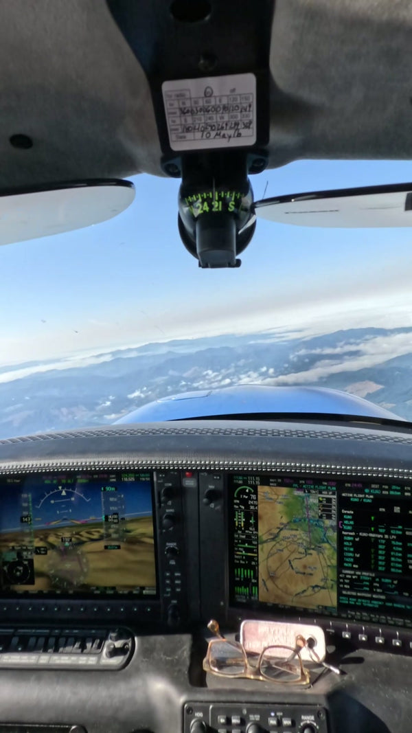 Cockpit instrument displays with mountains and clouds beyond the windscreen.