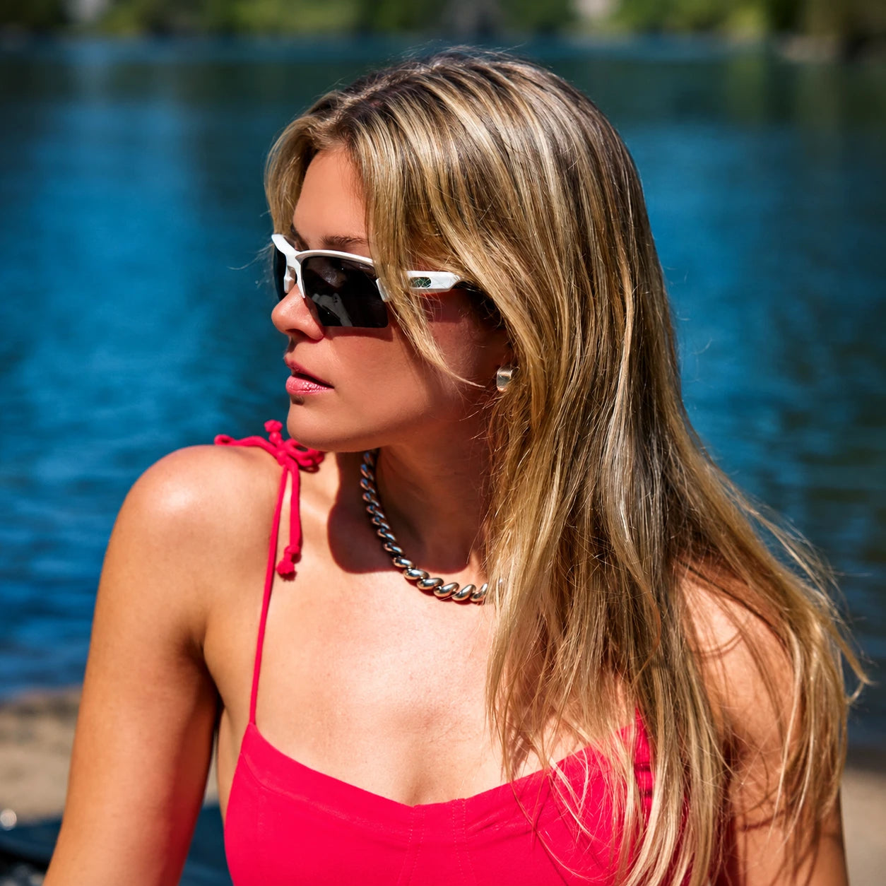 Woman wearing white Torque sunglasses and a red top beside a lake