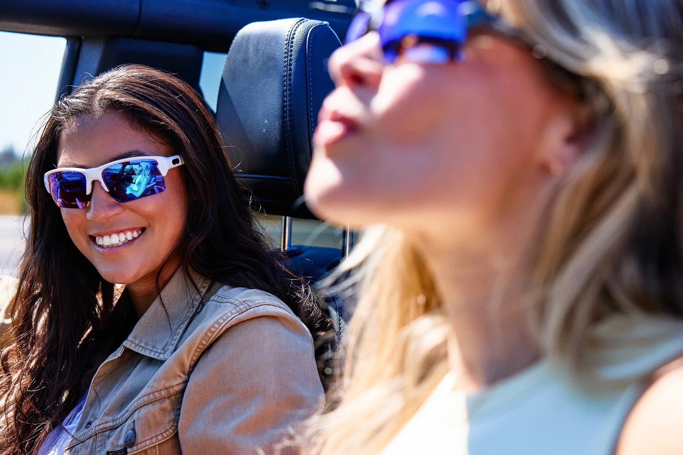 Two women wearing blue mirrored Torque sunglasses in a convertible