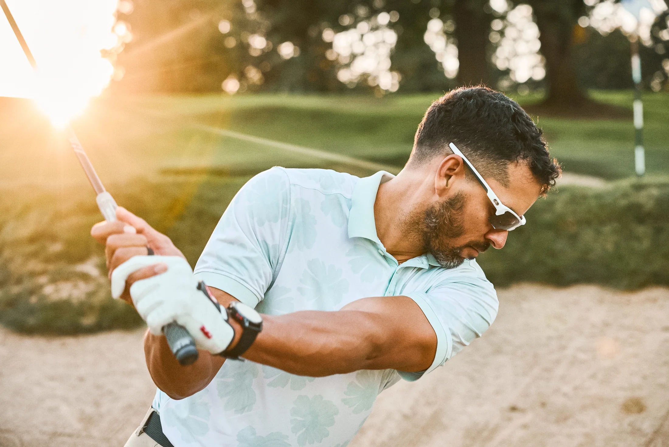 Golfer wearing white Torque sport sunglasses during a backswing