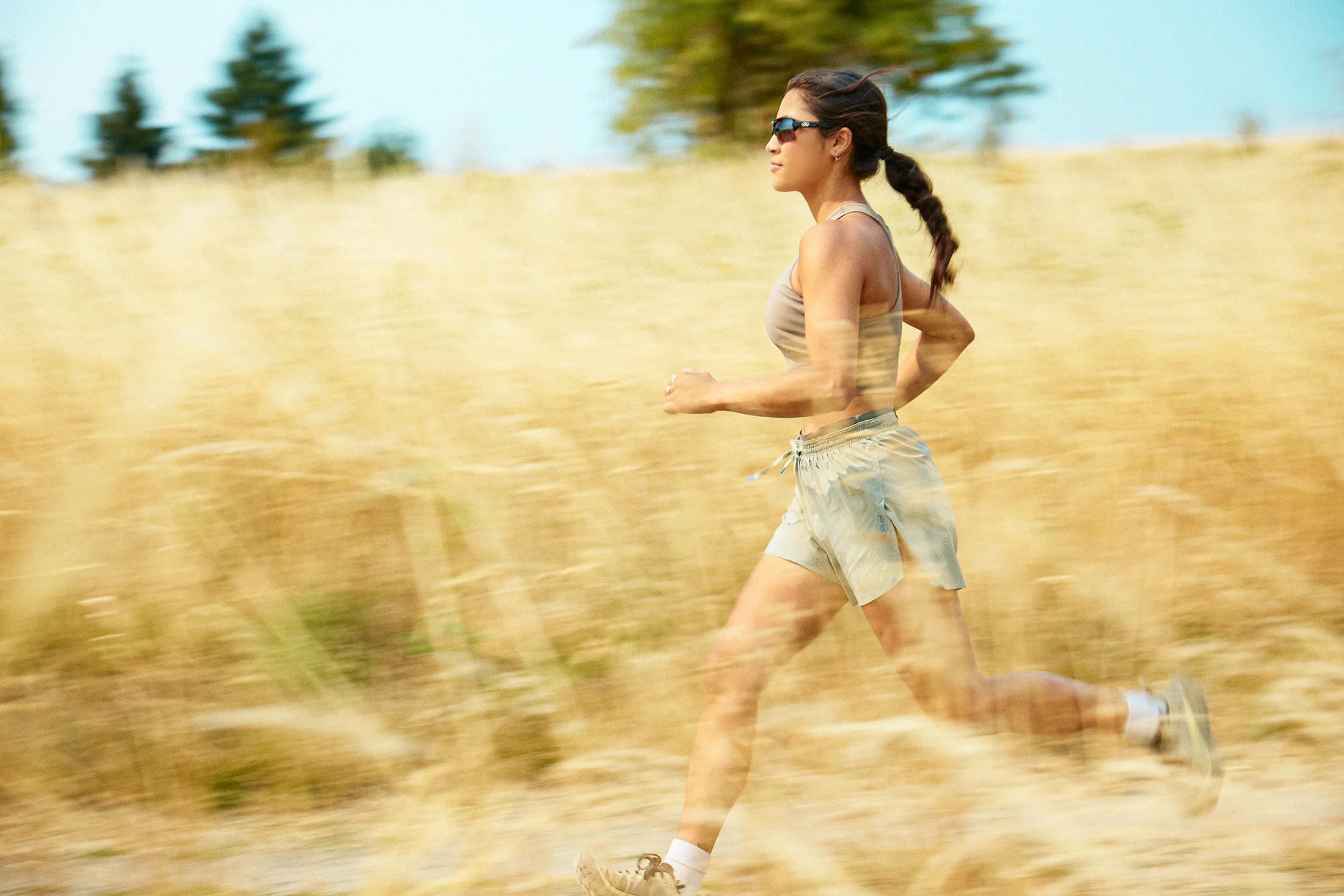 Woman running through a golden field wearing Torque sunglasses