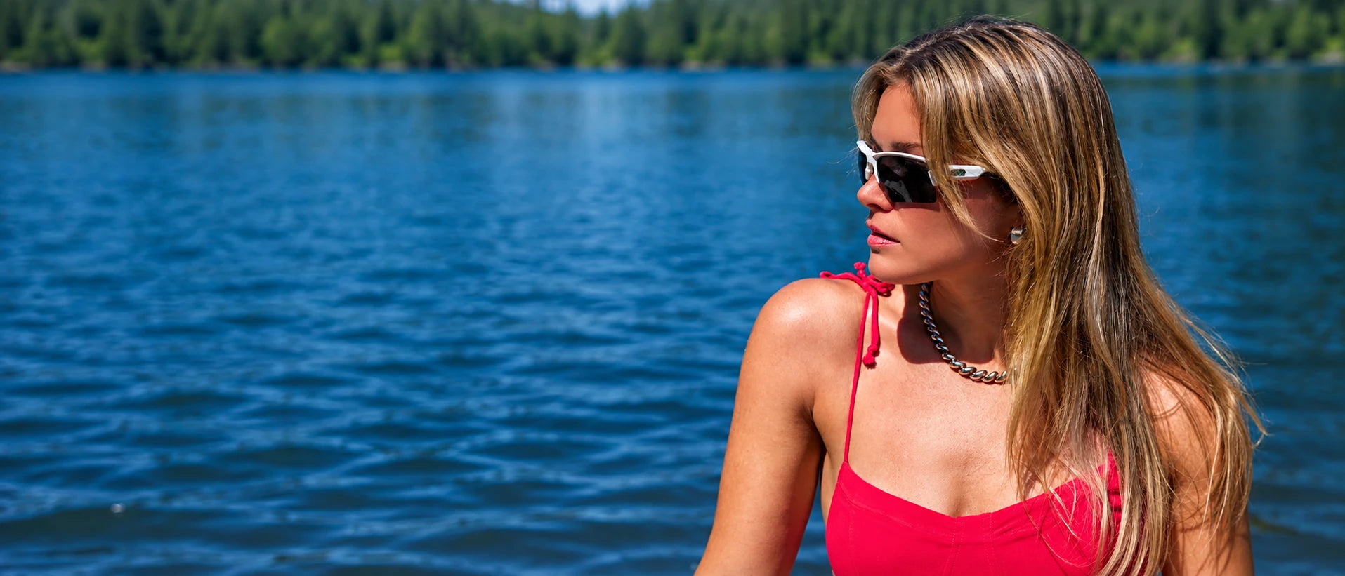 Woman wearing white Torque sunglasses and a red top beside a lake