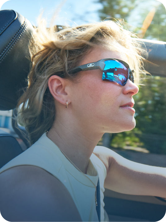 Driver wearing Torque sunglasses with blue mirrored lenses in a convertible