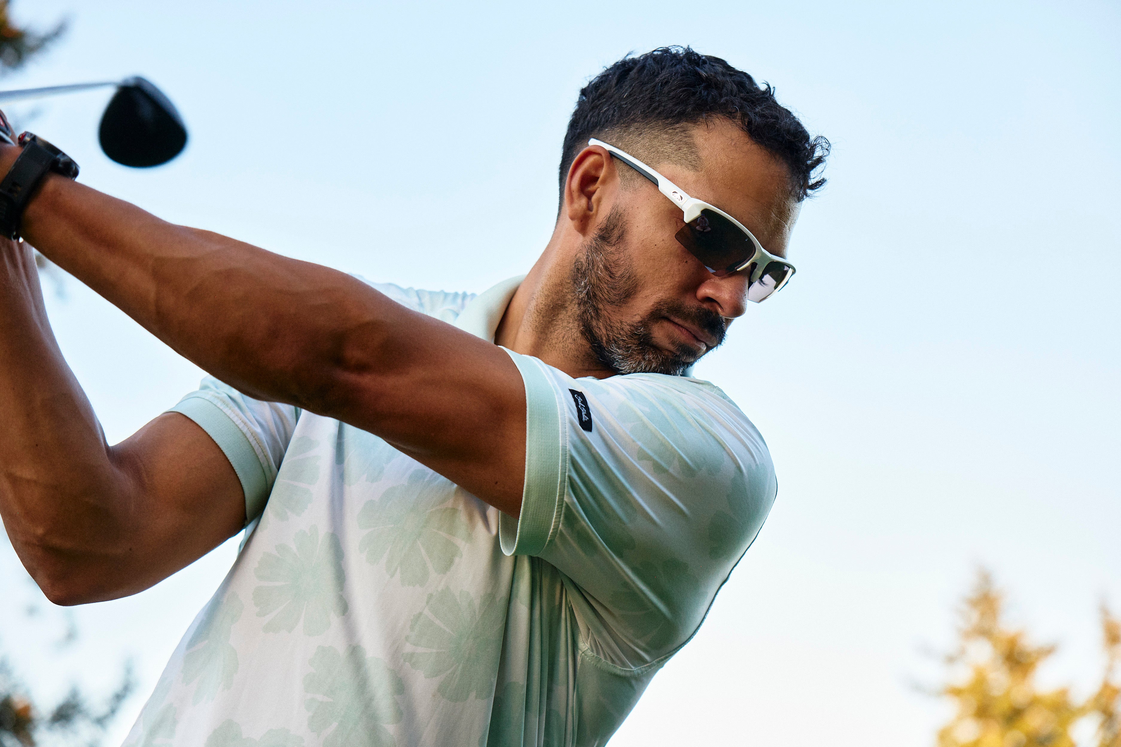 Golfer wearing white Torque sunglasses during a swing