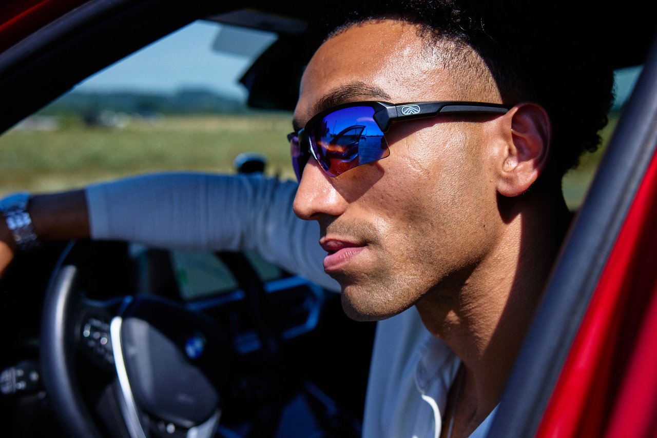 Man wearing black Camber sunglasses with blue mirrored lenses in a red car