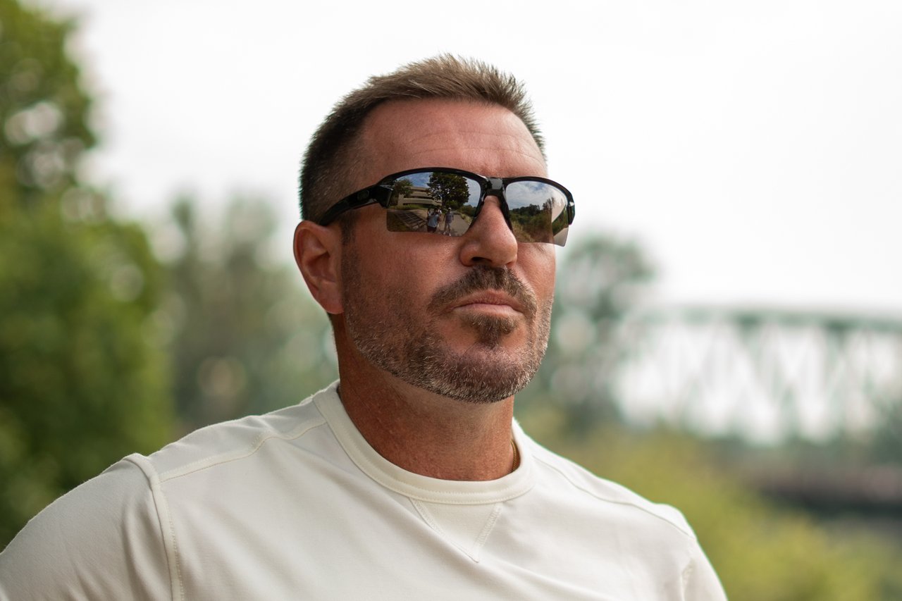 Man wearing black Camber sunglasses and a white shirt outdoors
