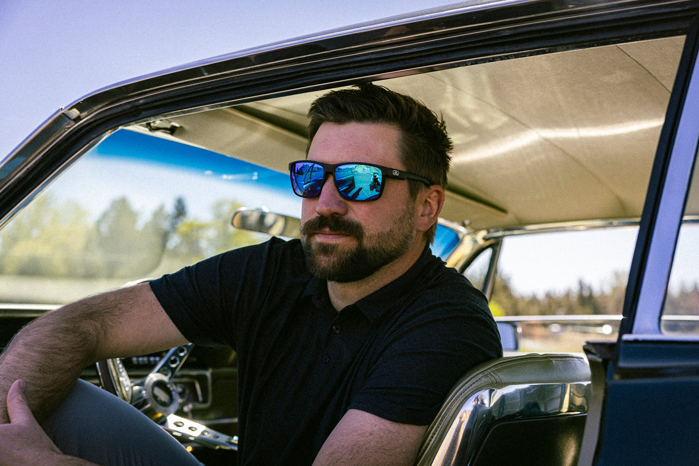 Driver wearing blue mirrored Torque sunglasses in a car
